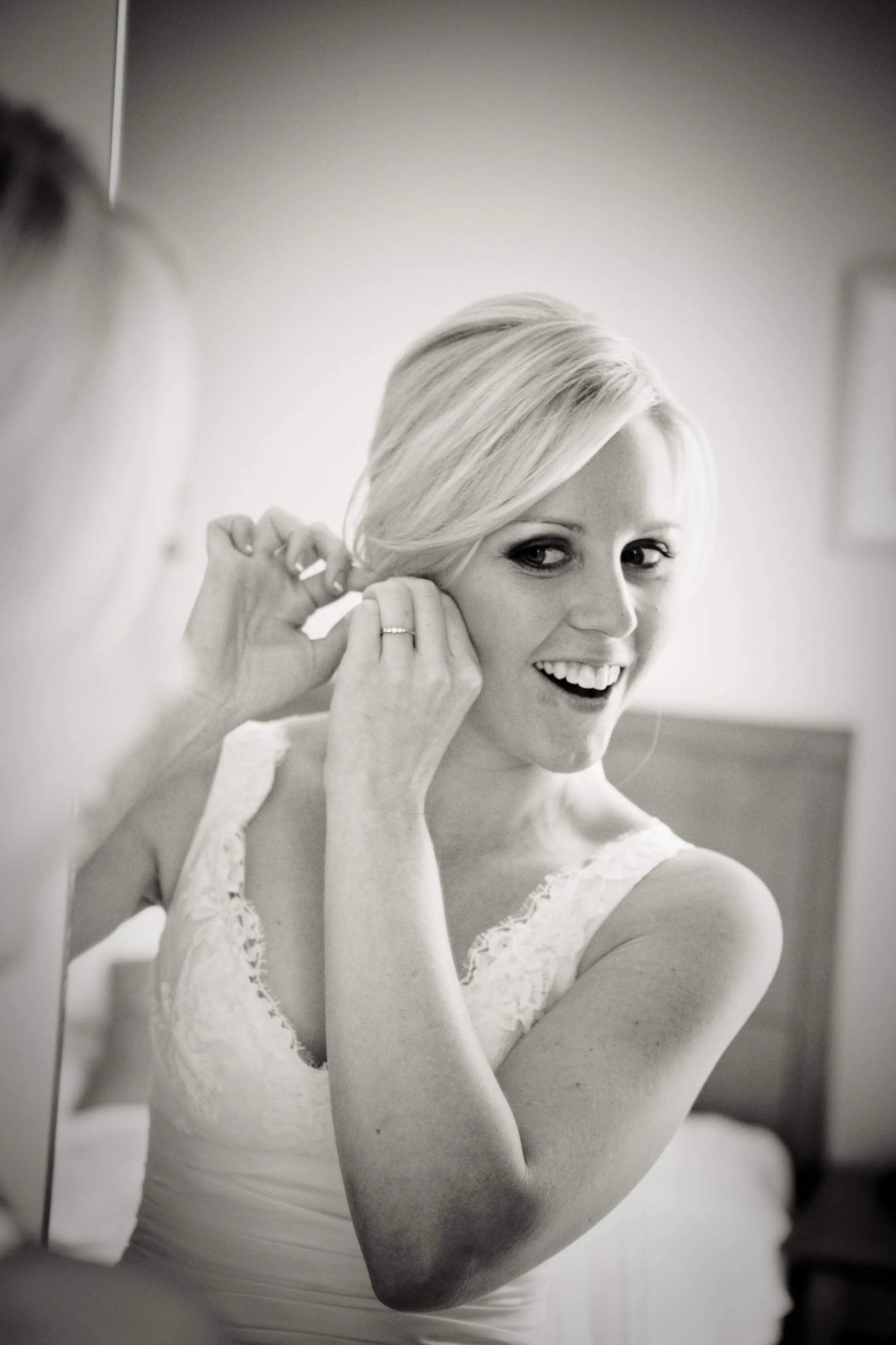 A Bellus bride fastening an earring, her hair styled half up half down