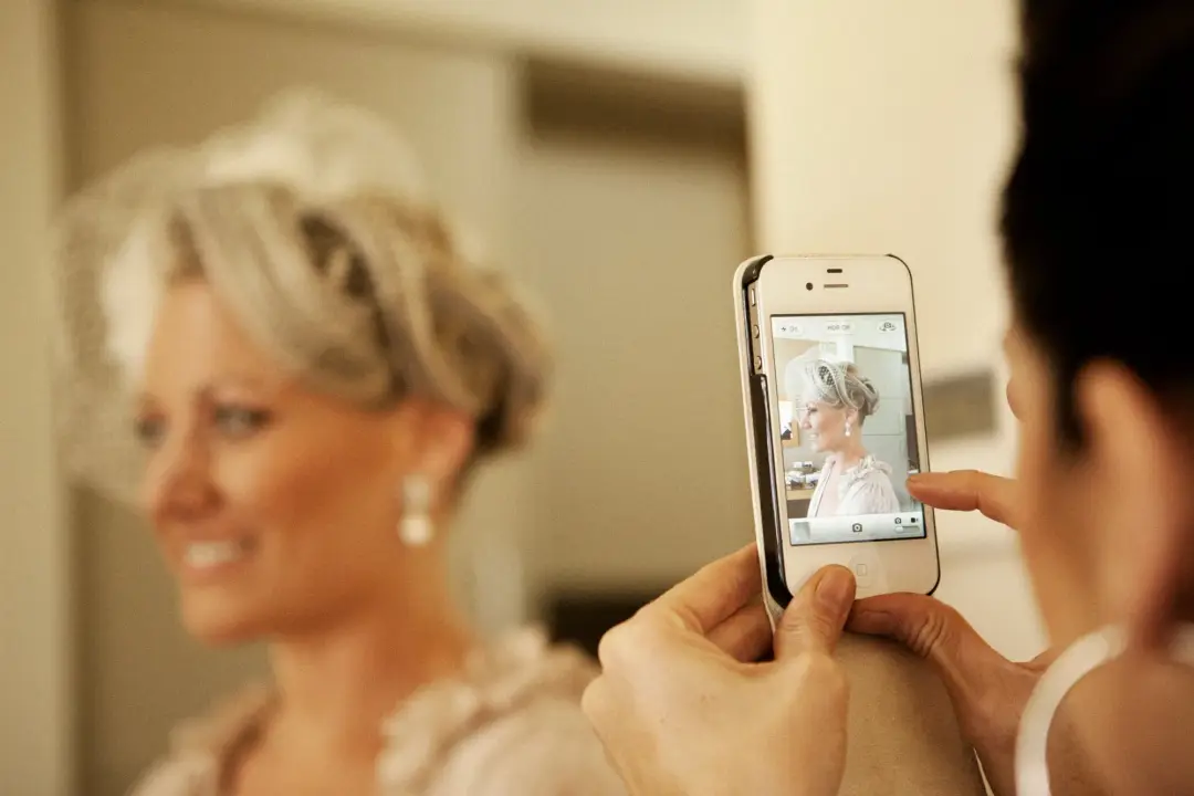 Bride photographed on a phone screen on the wedding morning, her hair styled and her veil already in