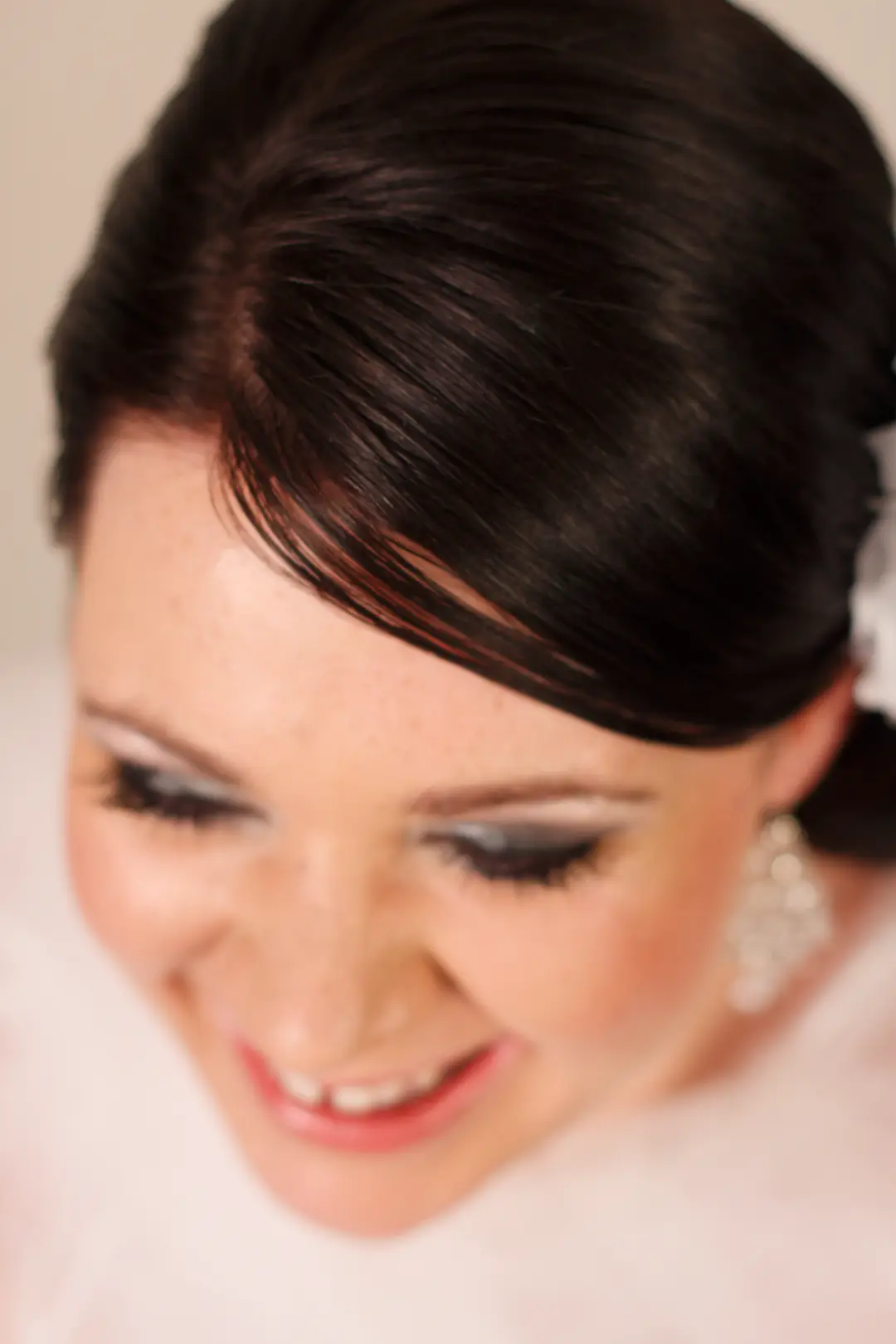 Dark hair swept into a smooth side style, worn with silver eye makeup and a crystal earring