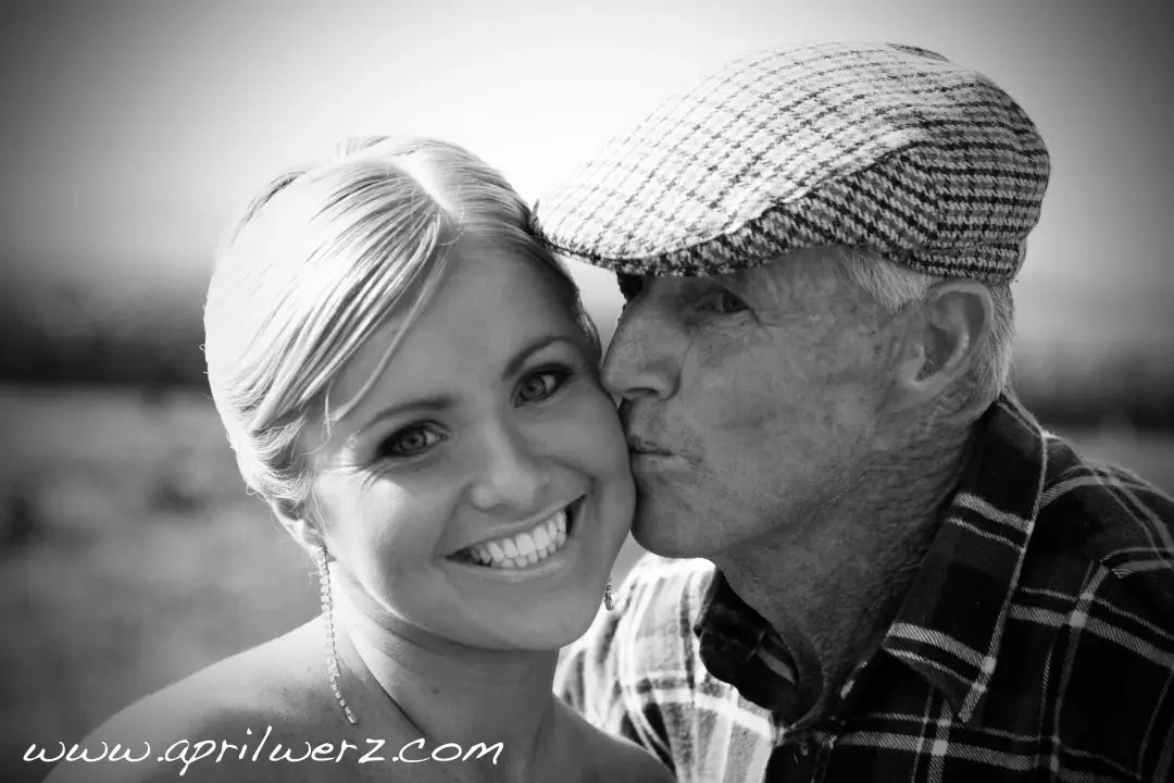 Guest kissed on the cheek by an older man, her blonde hair pinned back off her face