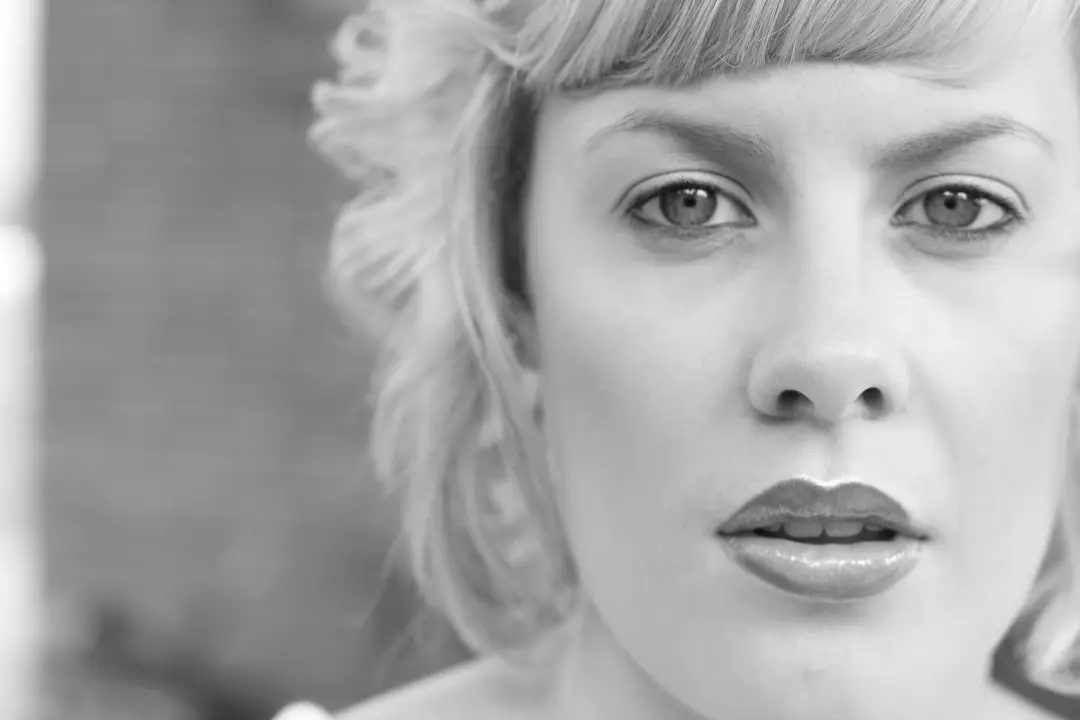 Close portrait of soft natural bridal makeup with a matte lip and a flower pinned at the crown