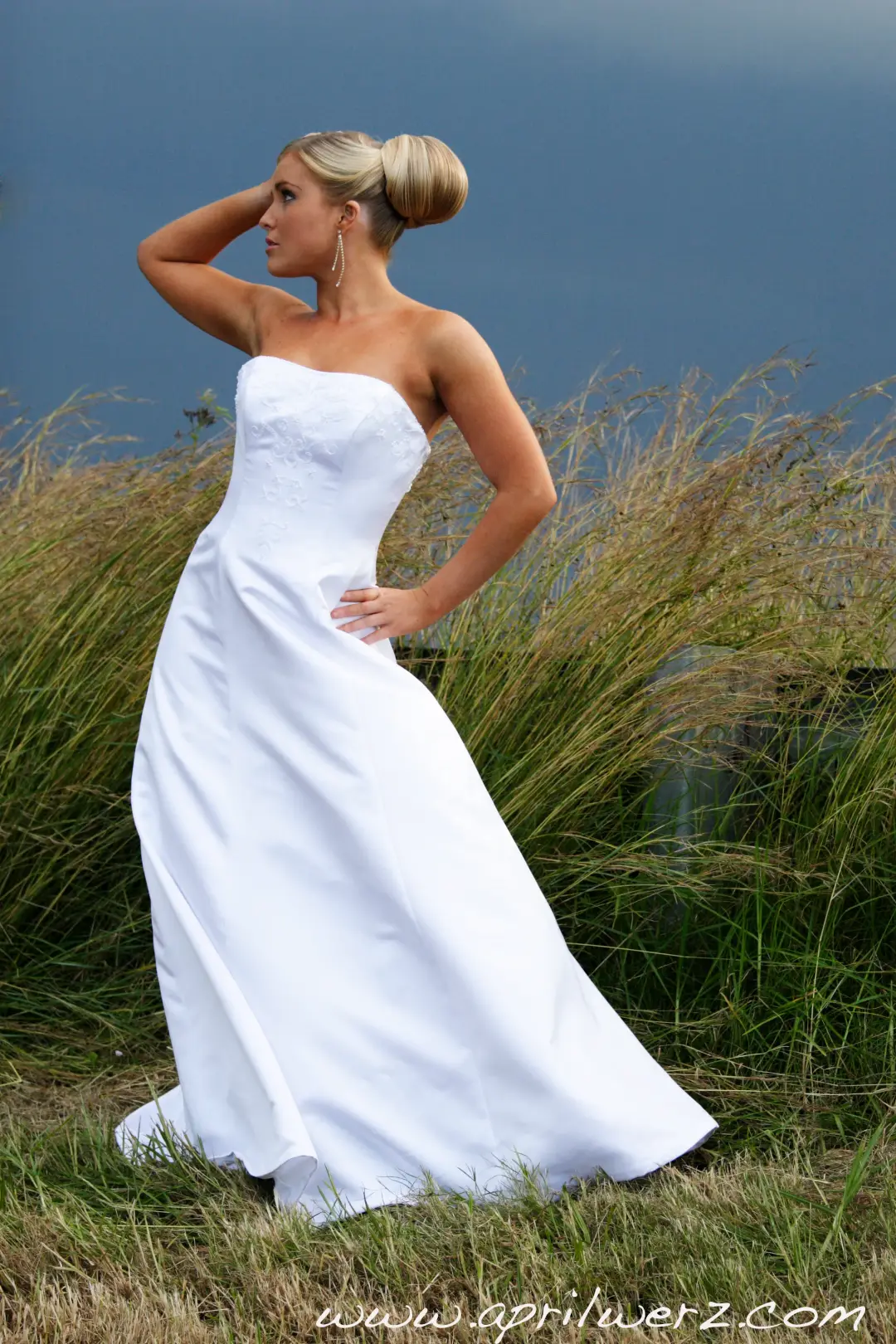 Bride in the dune grass, her blonde hair set in a smooth high bun