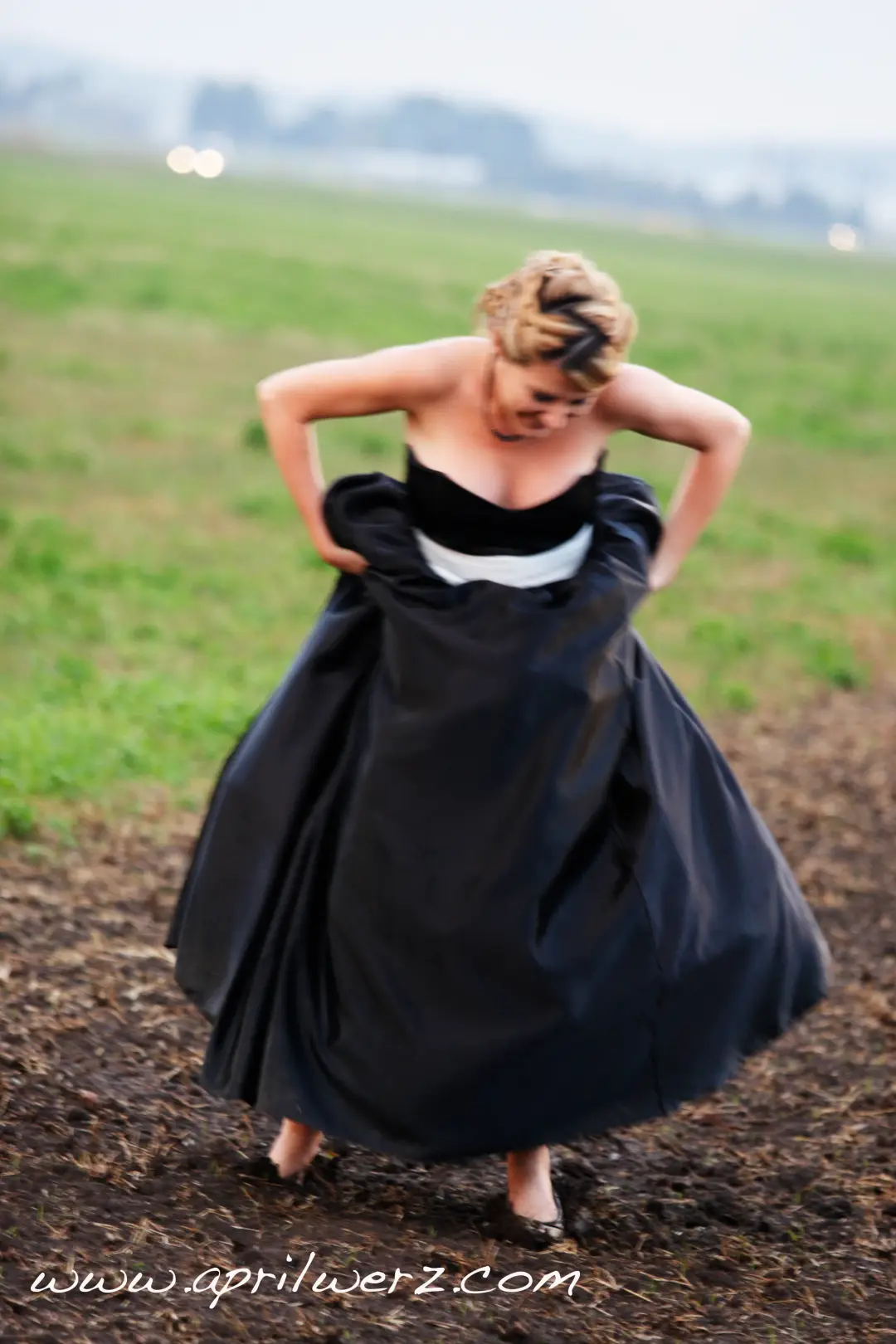 Guest in a black gown in a paddock, her blonde hair twisted into a pinned updo