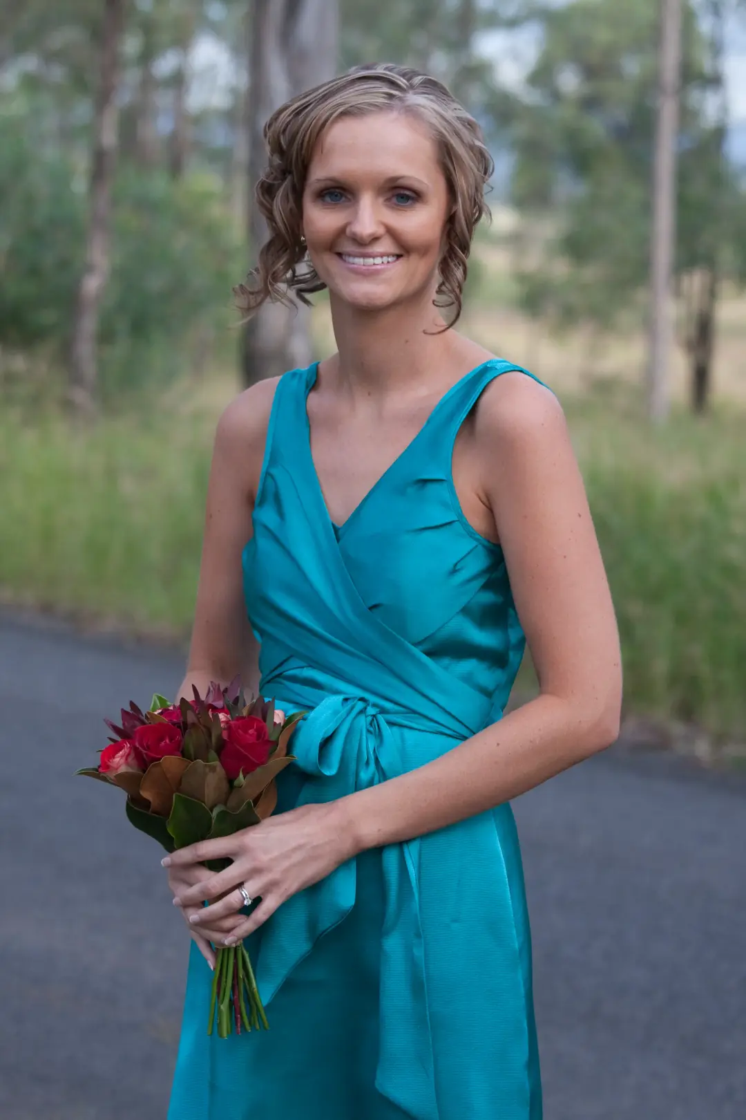 Mother of the bride in teal, her blonde hair pinned into a soft curled updo with a native posy