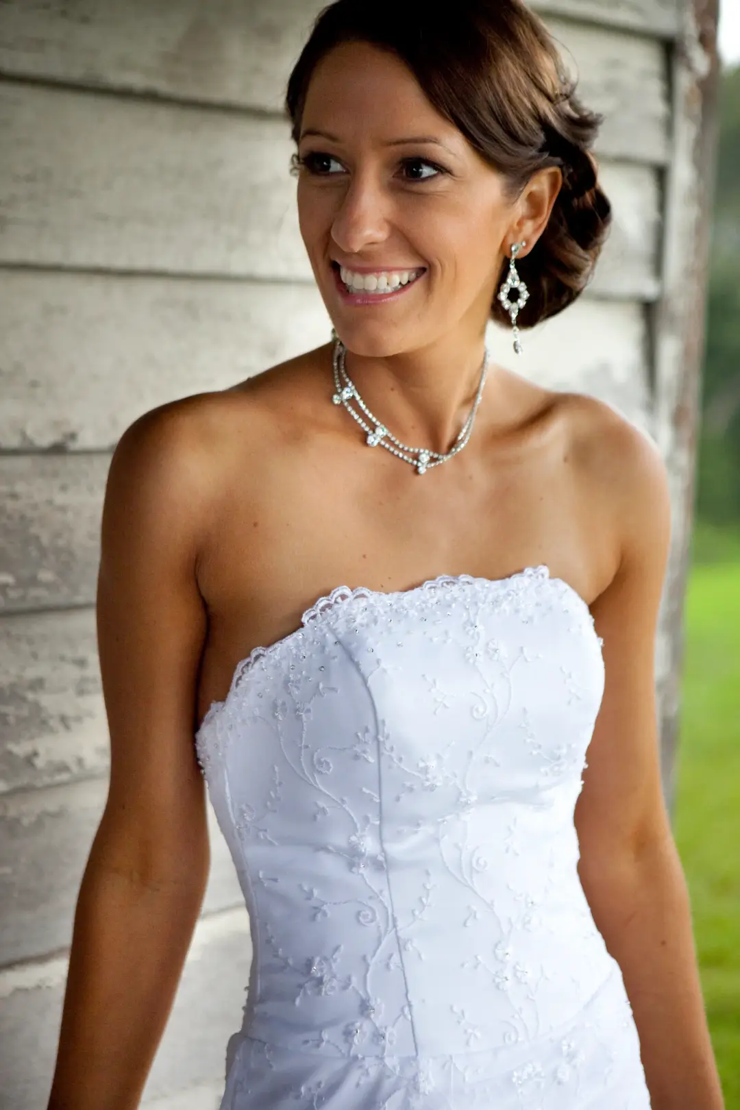 Bride in a strapless lace gown with her dark hair twisted into a low side updo