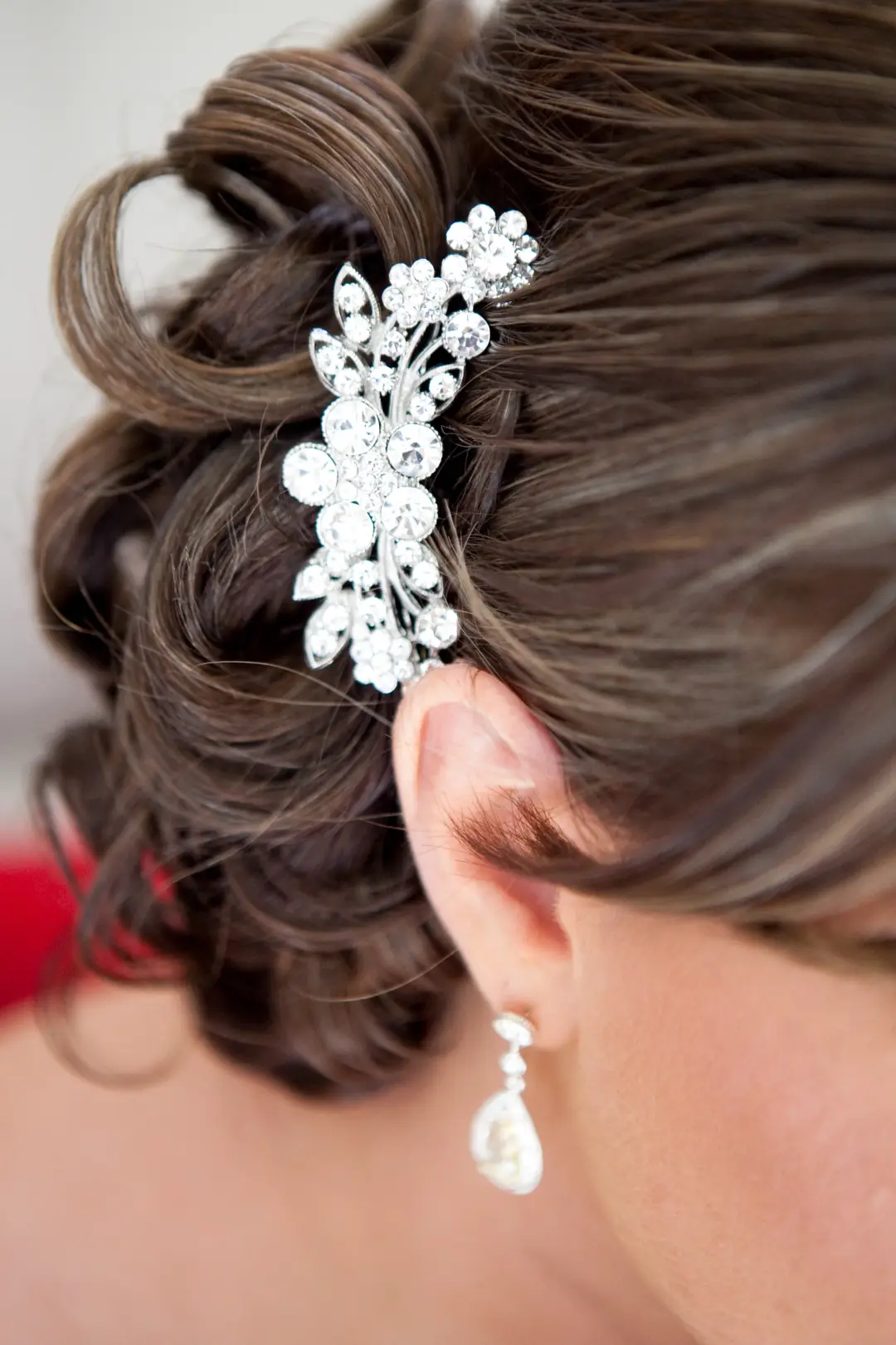 Crystal floral comb pinned into a brunette updo beside a pearl drop earring