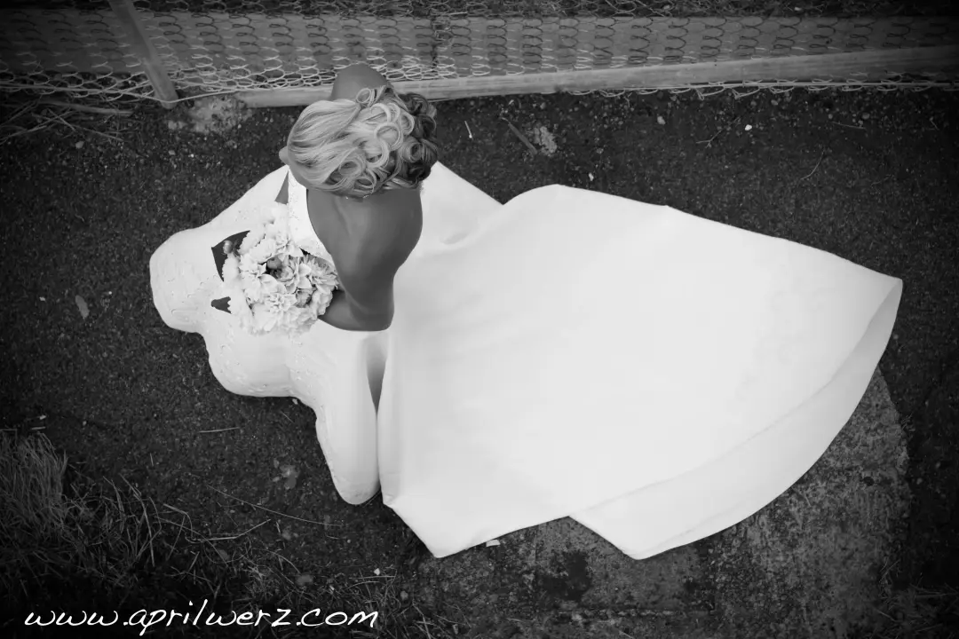 Bride lying on the grass photographed from above, her hair pinned with a fabric flower