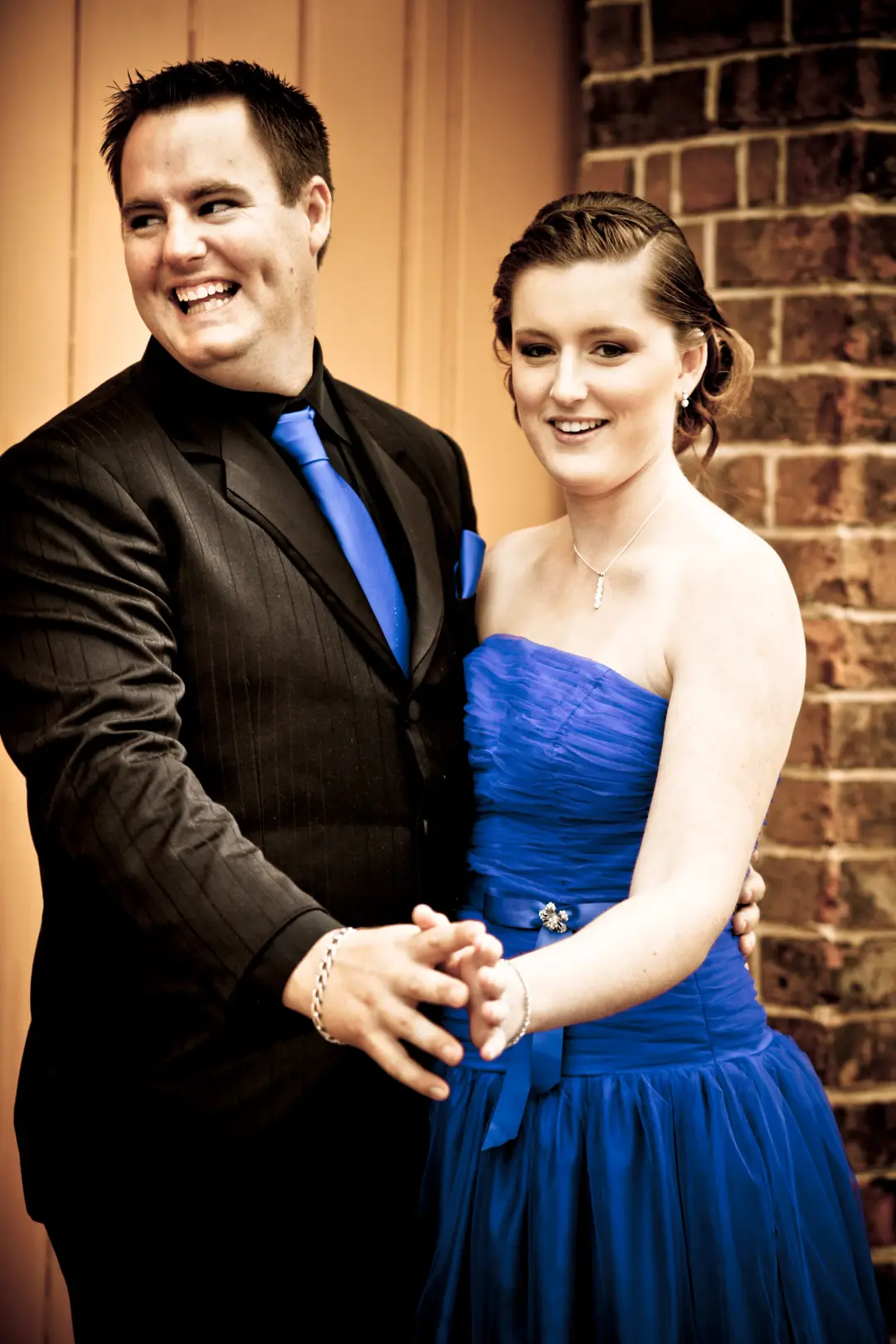 Couple at a formal, the guest's hair pinned into a smooth low style with a blue gown