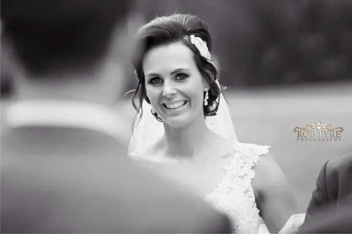 Bride laughing at her ceremony, her dark hair pinned up with a hairpiece under the veil