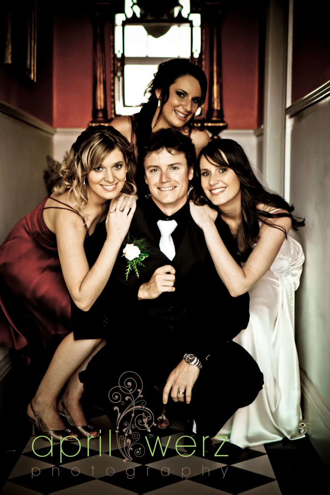Groom on the stairs with three guests, all three styled with their hair worn down and pinned back