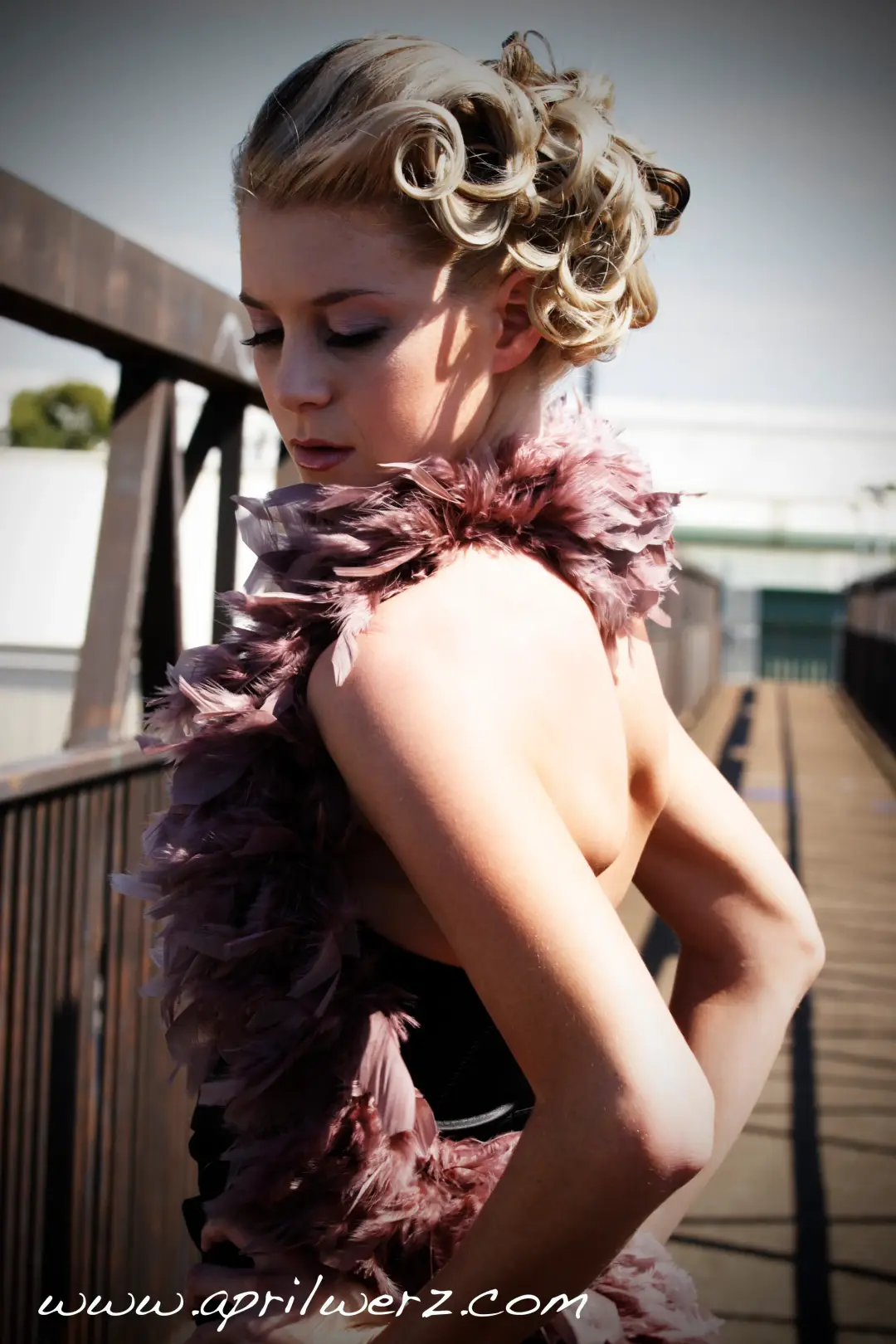 Blonde curls pinned into a high vintage updo, photographed on the boardwalk with a feather wrap