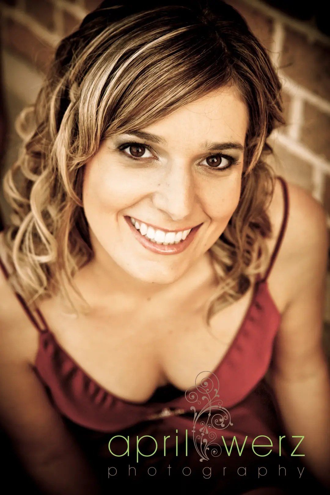 Guest against a brick wall with her hair pinned up and curls left loose at the front