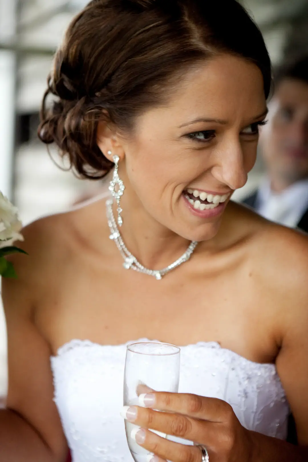 Bride laughing with a glass in hand, her brunette hair pinned into a soft low updo