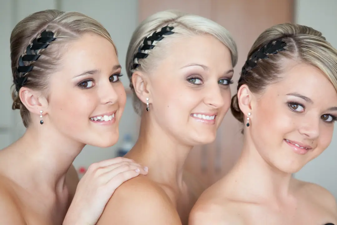 Three bridesmaids styled together in braided crowns, each wearing a soft smokey eye