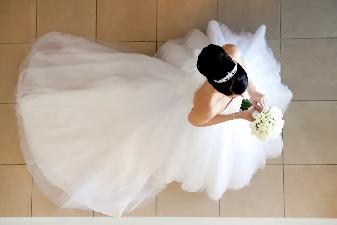 Bride photographed from above with her tulle skirt spread, her dark hair pinned under a headband