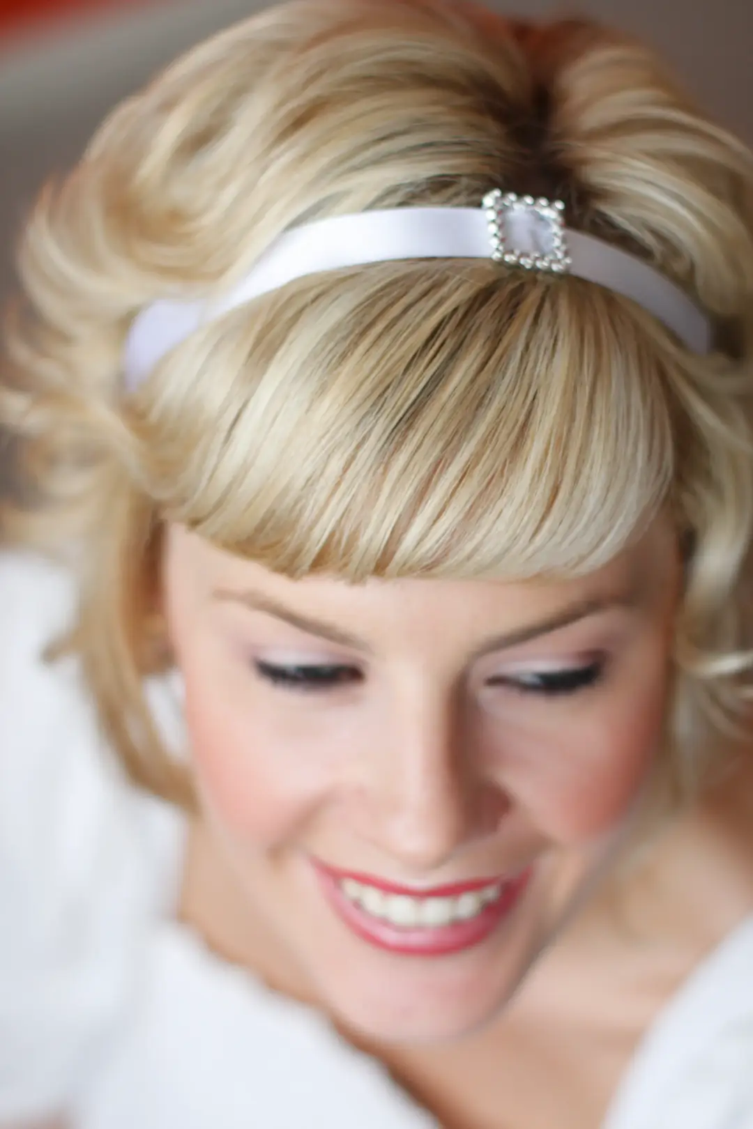 Short blonde hair styled with a soft fringe and a satin headband with a pearl clasp