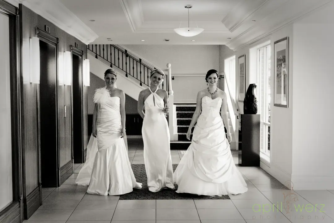 Bride and two bridesmaids walking a hotel corridor, hair pinned and veils in