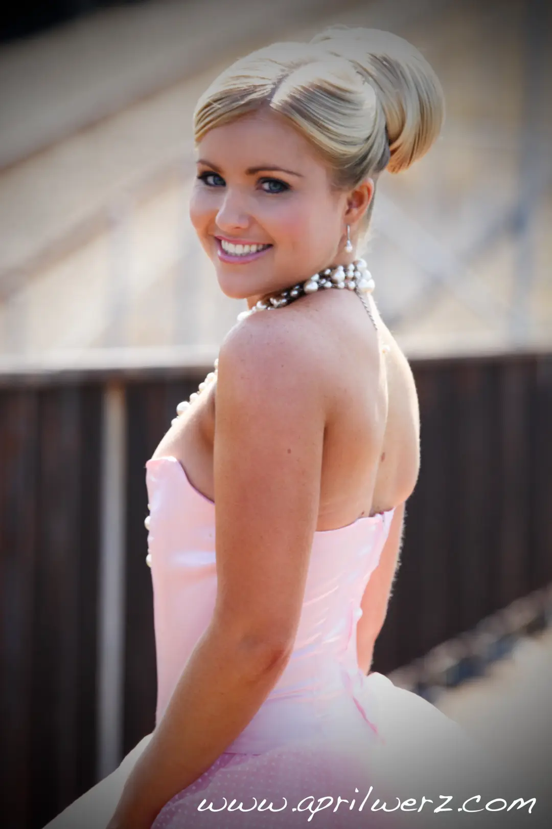 Guest in a pink gown with her blonde hair wound into a sleek high bun and a pearl choker
