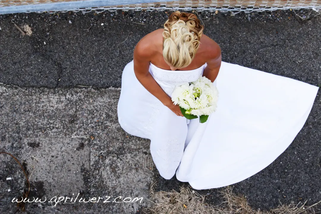 Bride from above on the sand, her blonde hair pinned into a curled updo