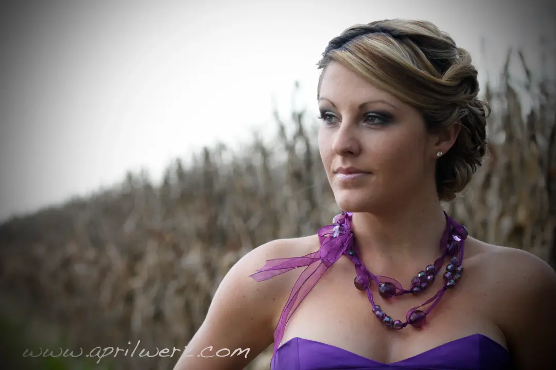 Guest in a purple gown with her blonde hair twisted into a braided updo, wearing a violet smokey eye