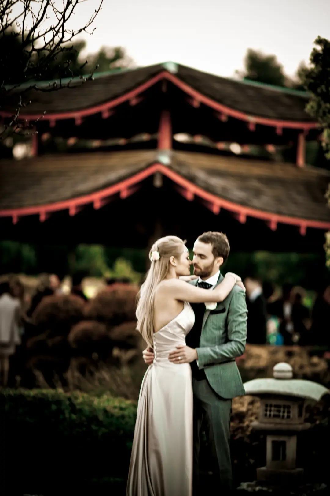 Bride and groom in a Japanese garden, her long blonde hair worn down with a flower pinned at the side