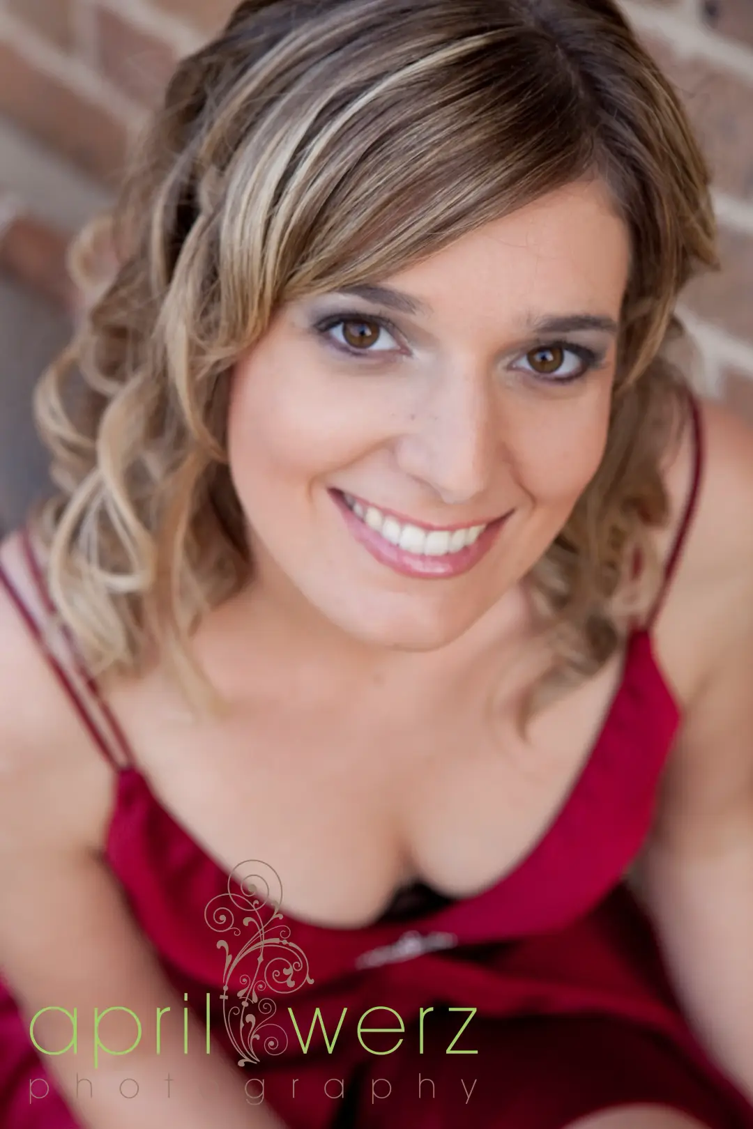 Formal portrait in a red dress, the hair in soft curls with a half up finish and a smokey eye