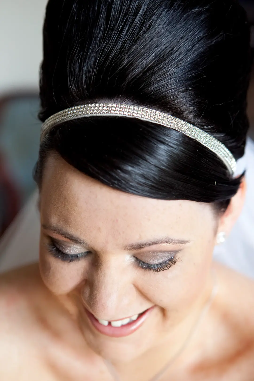 Bride in a dark beehive style with a diamante headband, wearing soft champagne eye makeup