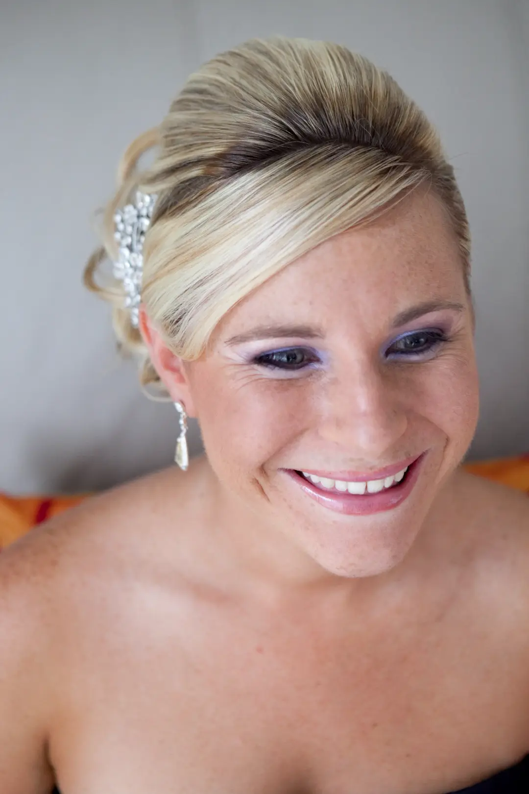 Bride in a smooth blonde updo with a crystal hairpiece and lilac eye makeup