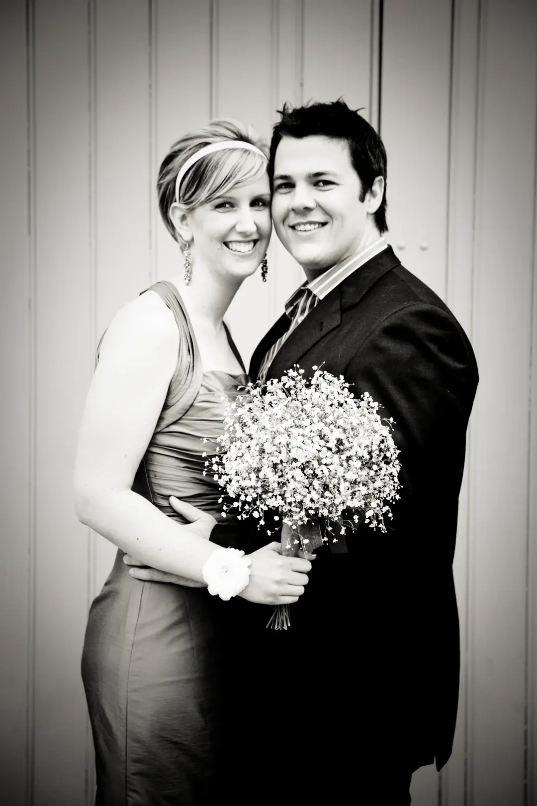 Wedding guest in a taupe dress with a short blonde style, holding a bouquet of baby's breath