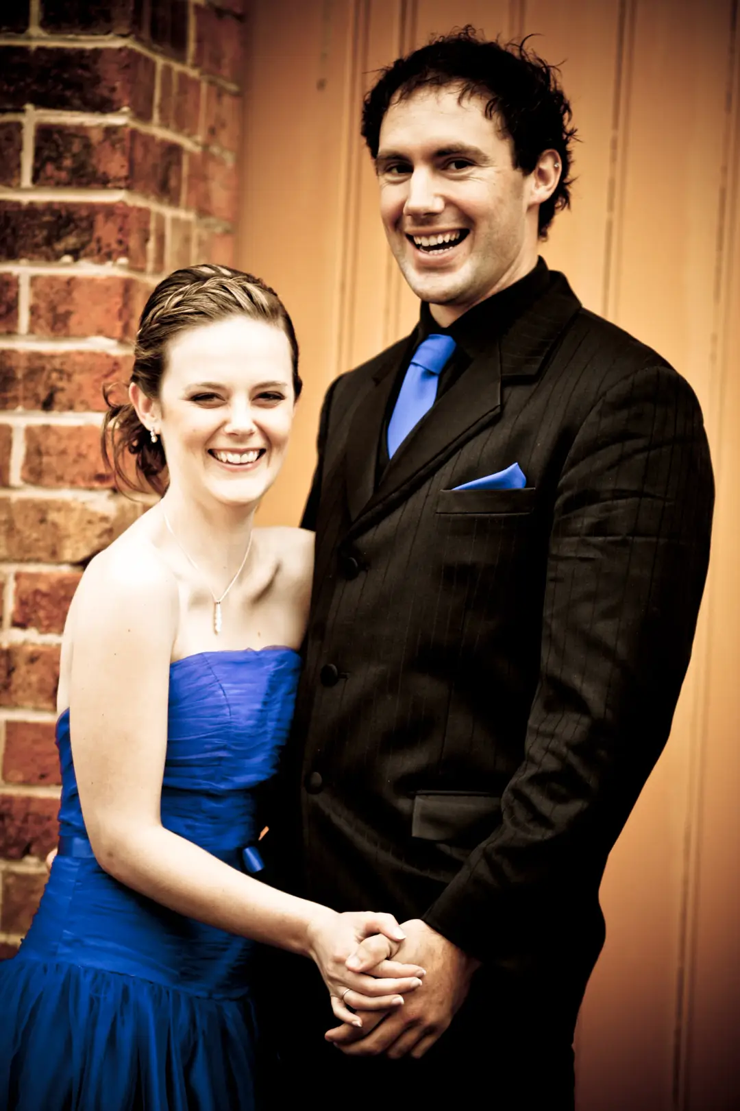 Couple at a formal, the guest's hair pinned up loosely with a blue gown