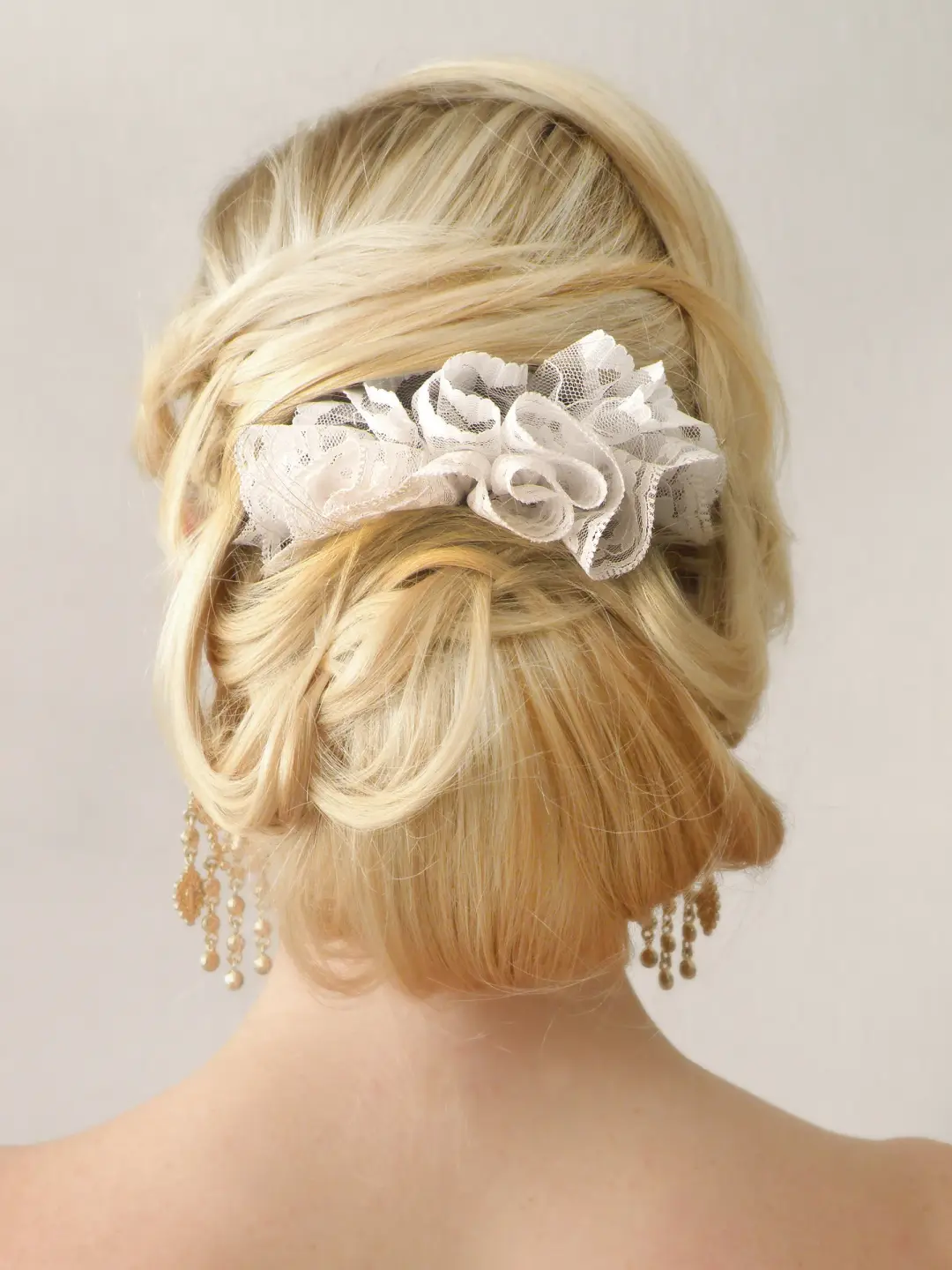 Back view of a blonde upstyle dressed with a lace hairpiece and beaded drop earrings