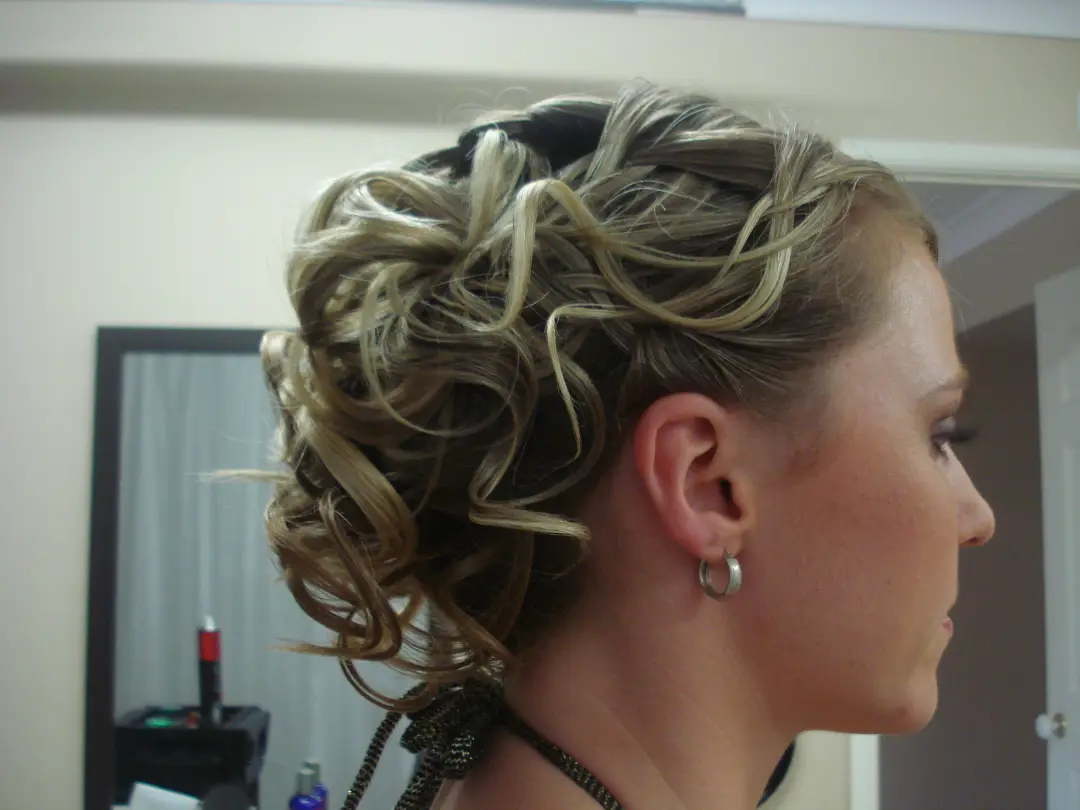Side view of a curled upstyle on highlighted blonde hair, dressed with loose ringlets