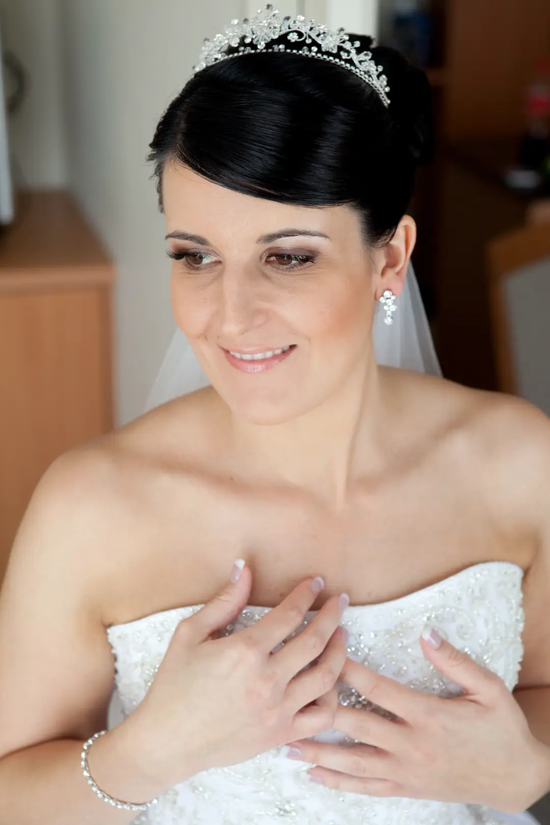 Bride in a jewelled tiara with her dark hair swept into a smooth beehive, wearing soft neutral makeup