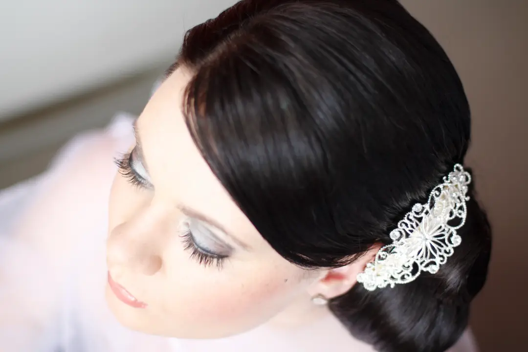 Dark haired bride in a smooth low bun with an ornate silver headpiece, wearing soft romantic makeup