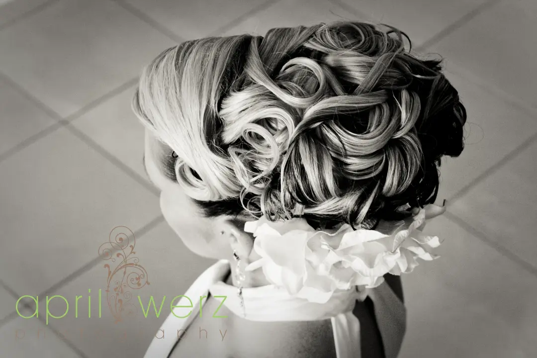 Back view of a full curled upstyle finished with a white flower