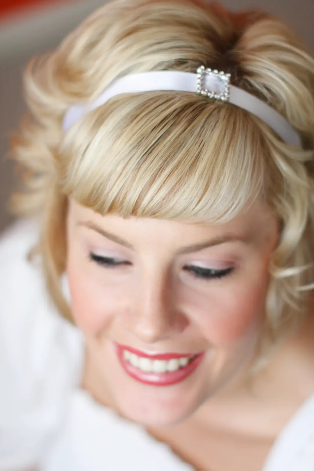 Bride with a short blonde style and a fringe, wearing a diamante headband and a soft pink lip