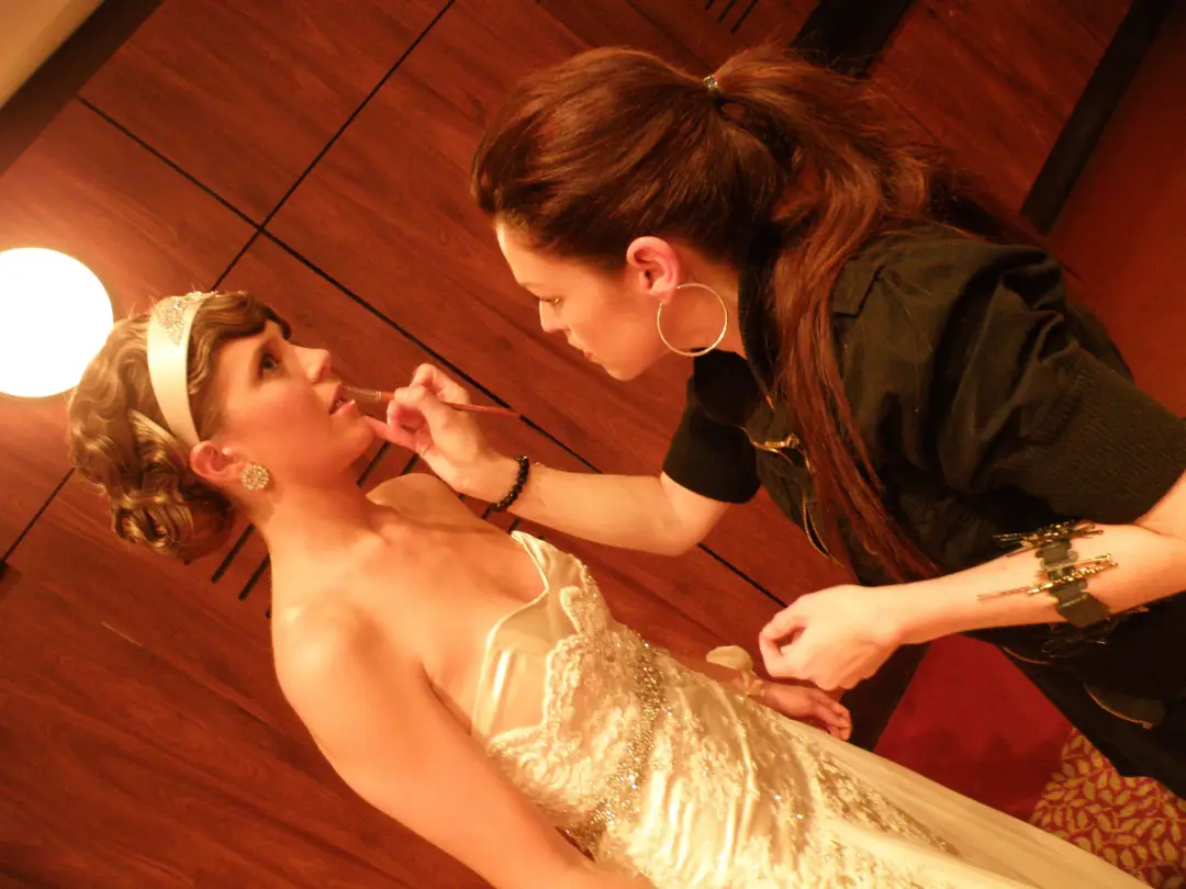 Bridal makeup applied on location by lamp light, the bride already wearing a headband and a pinned style