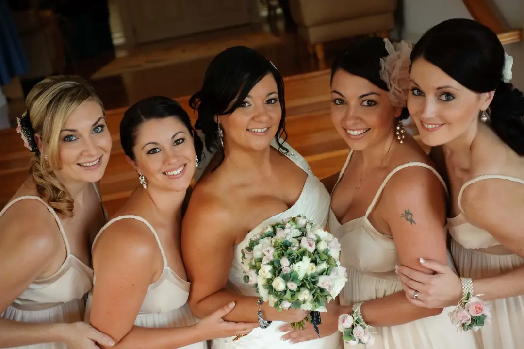 Bride and four bridesmaids in cream, every one styled with her hair worn long and pinned back