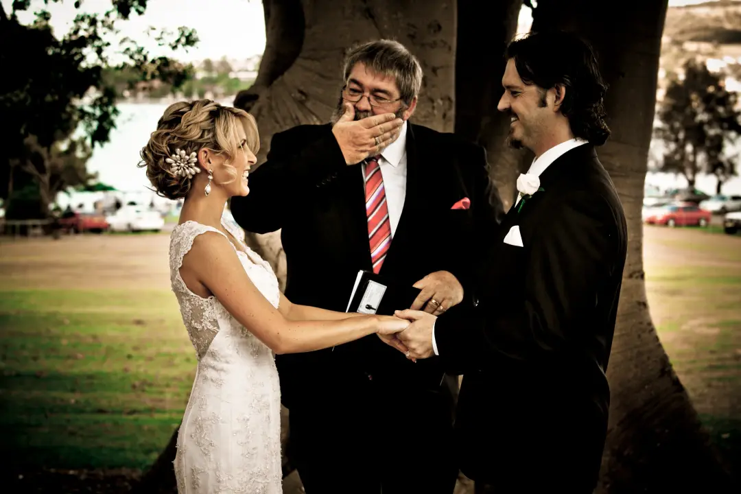 Bride and groom exchanging vows with their celebrant, her hair pinned with a floral comb, by Amanda Frost of Bellus