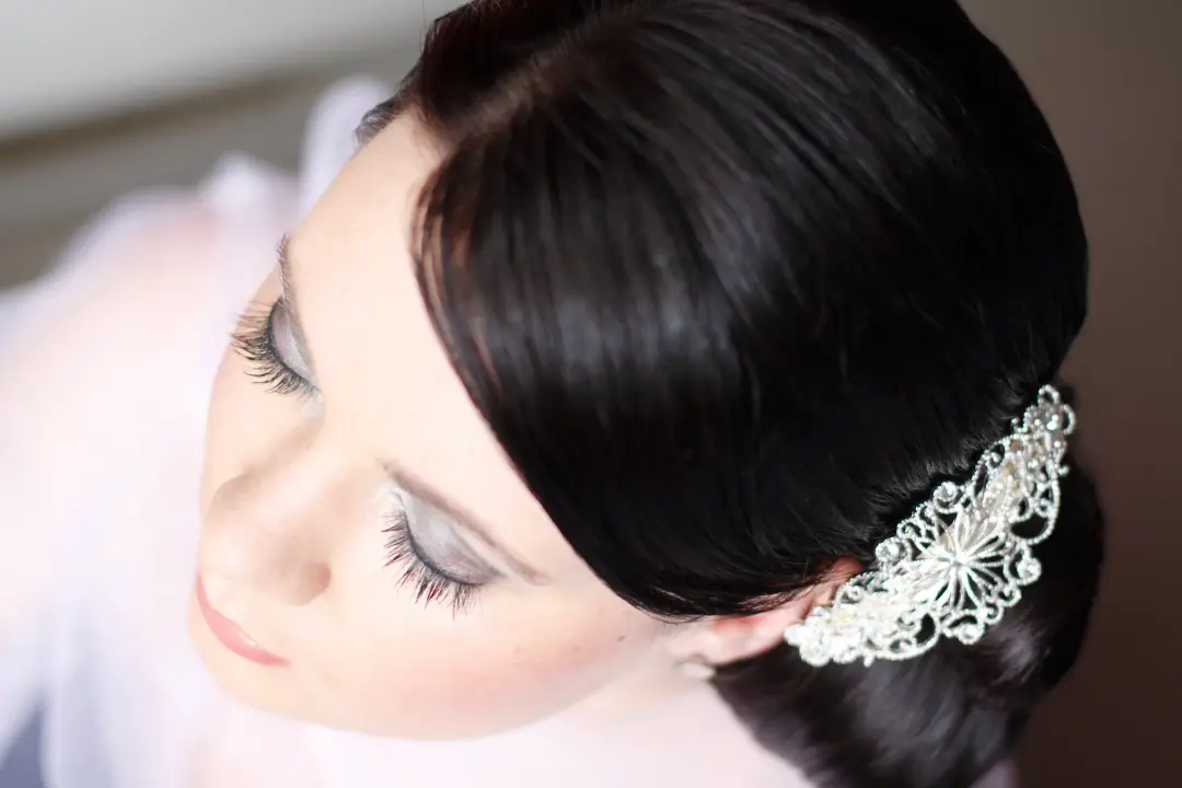 Dark hair set into a smooth side style with a lace comb, worn with a soft silver eye