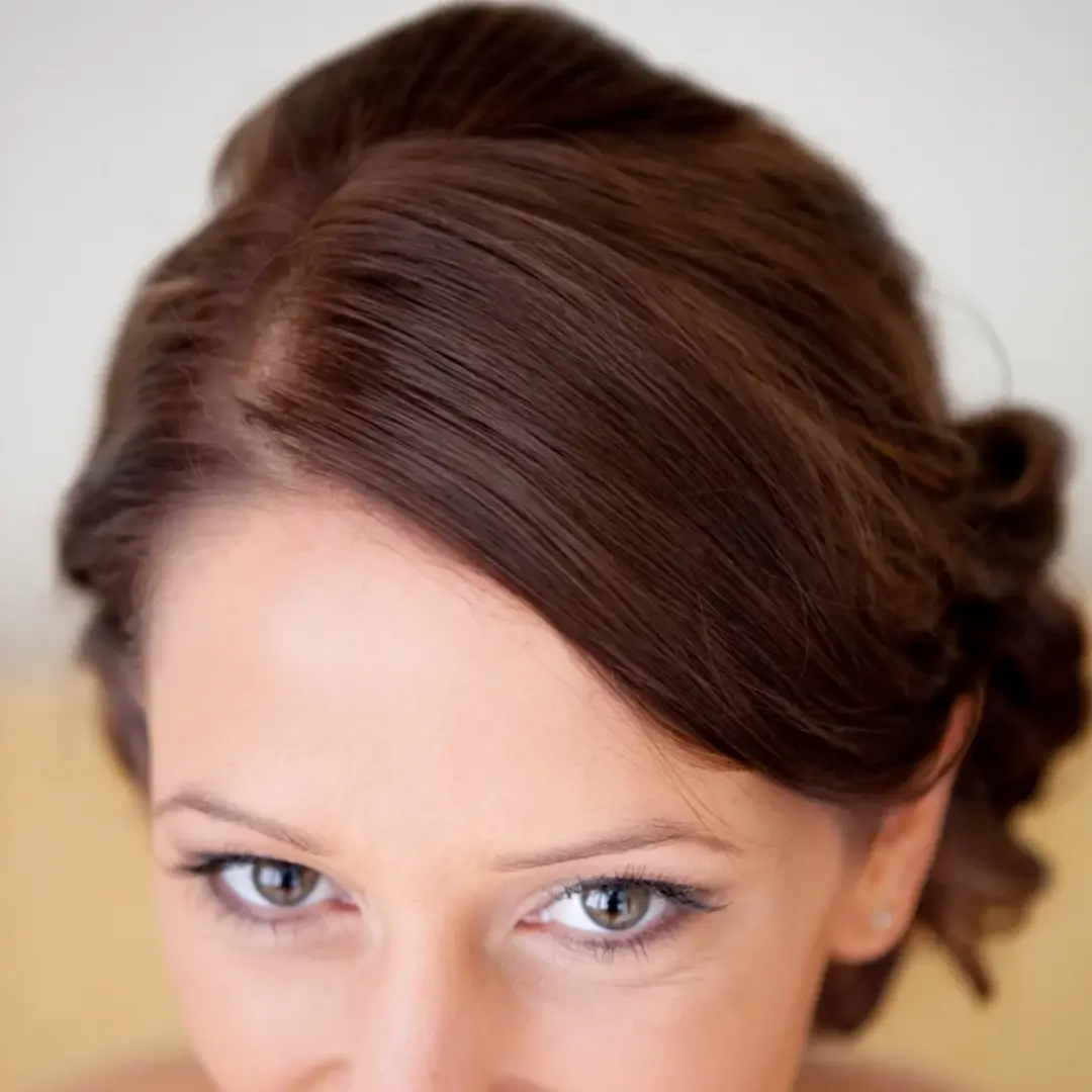 Auburn hair swept into a smooth pinned style, worn with soft neutral makeup