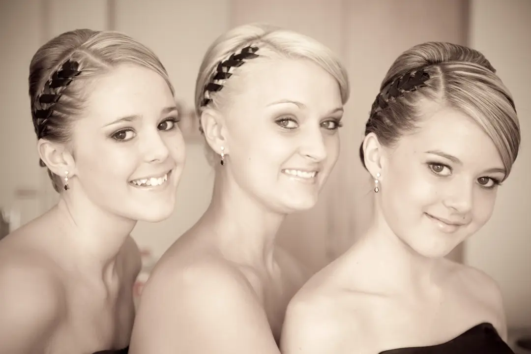 Three guests styled for a formal in braided crowns and smooth pinned finishes
