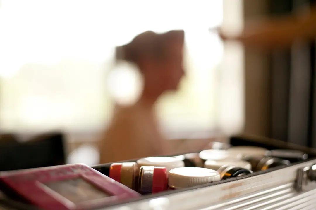 Open makeup kit on the bench at a bridal hair and makeup trial, the client blurred behind it