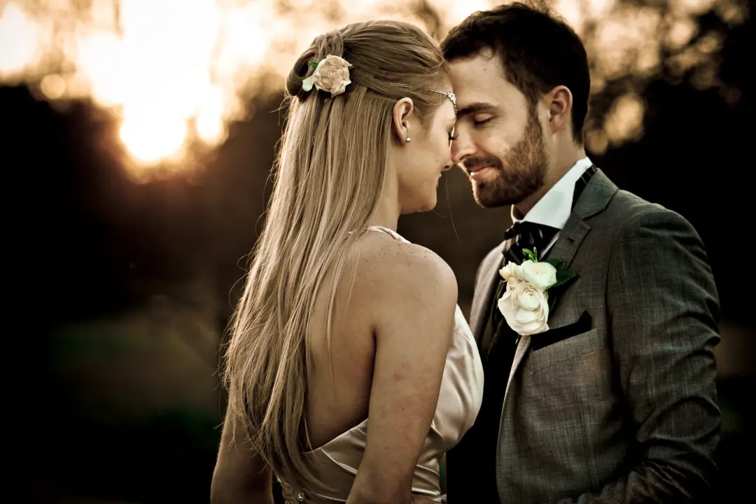 Couple eloping at sunset, the bride's long hair worn loose with a cream flower pinned at the side, by Amanda Frost of Bellus