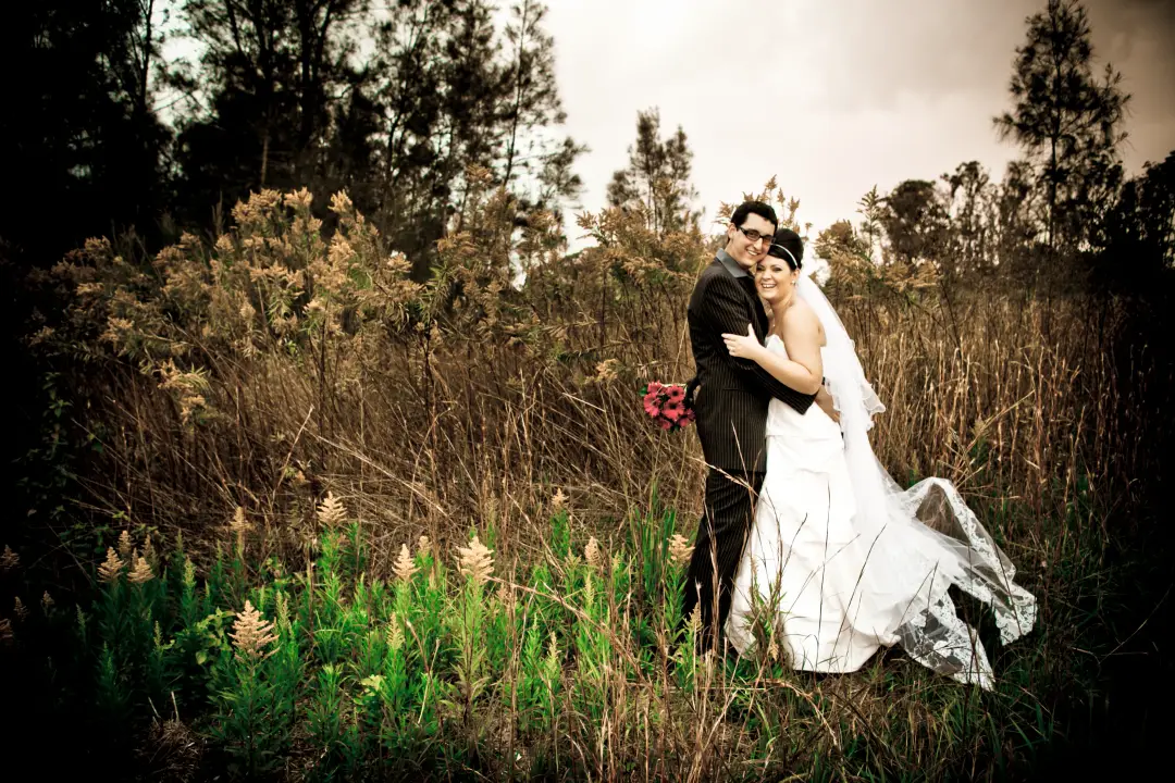Bride and groom embracing in a paddock at an intimate Central Coast wedding, the bride in a long veil, by Amanda Frost of Bellus