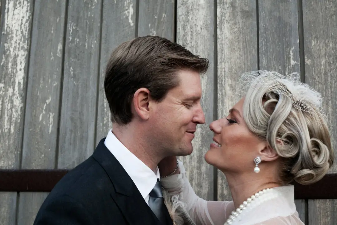 Bride and groom nose to nose against timber, her hair set in vintage curls with a birdcage veil, by Amanda Frost of Bellus