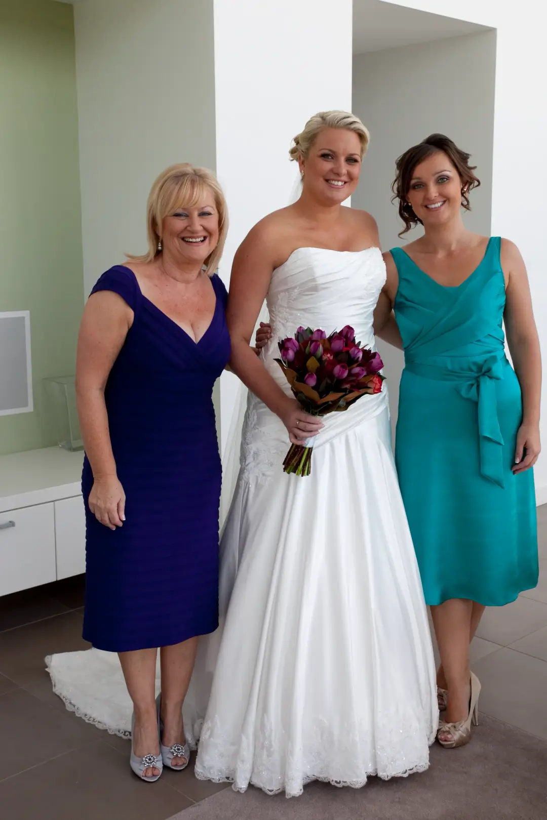 Bride between her mother and an aunt, all three styled for the day with hair pinned up