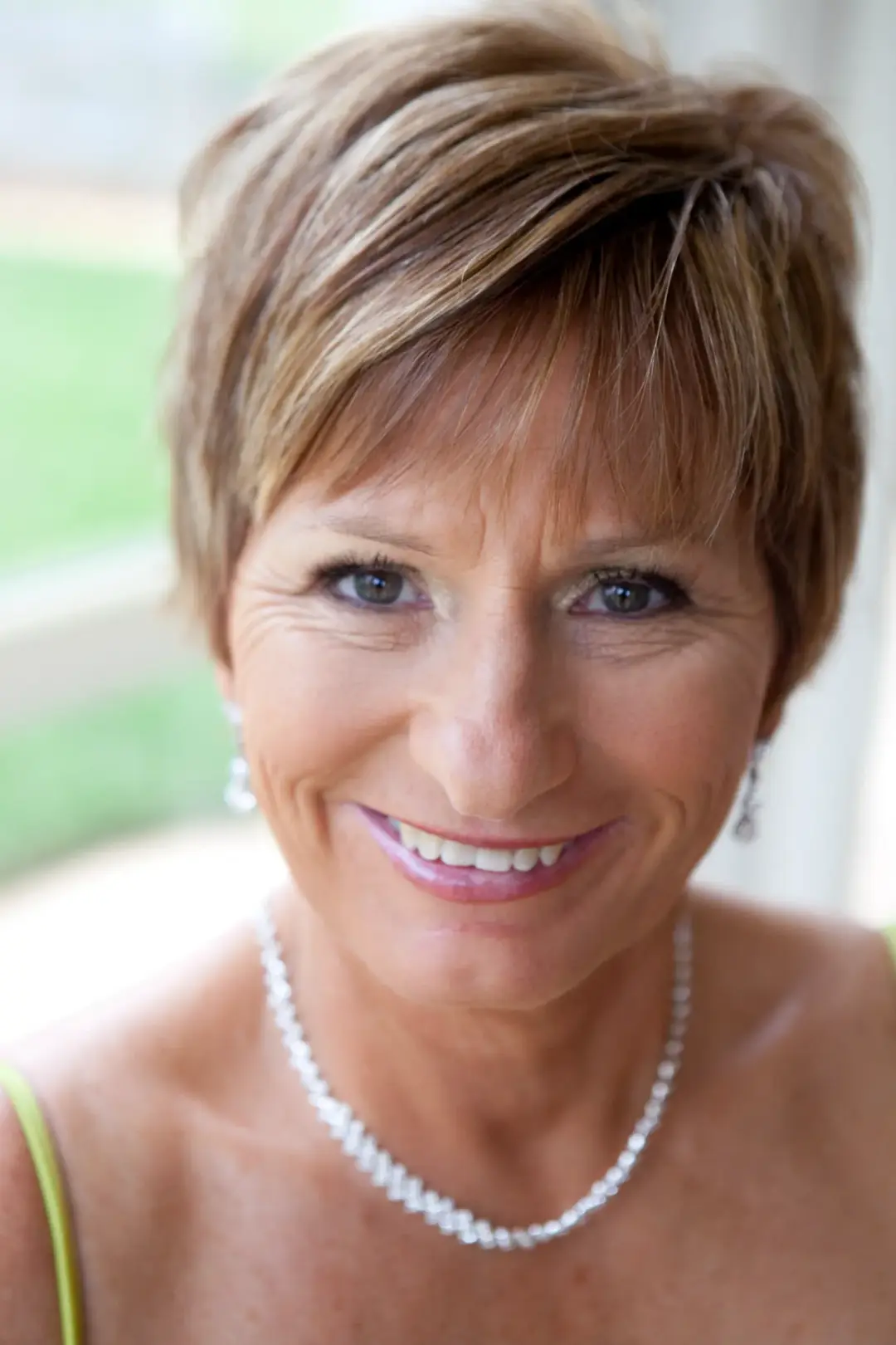 Mother of the bride with a short layered cut, wearing soft finished makeup and pearls