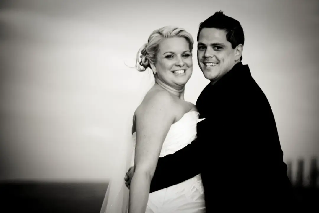 Bride and groom laughing together, her blonde hair pinned into a soft curled updo