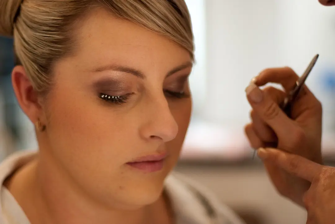 Traditional foundation and eye makeup applied by hand, the bride's blonde hair already pinned back